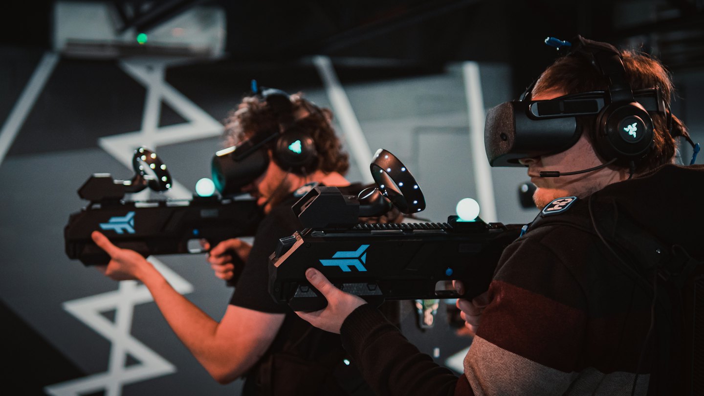 Two people playing a VR game with futuristic controllers.