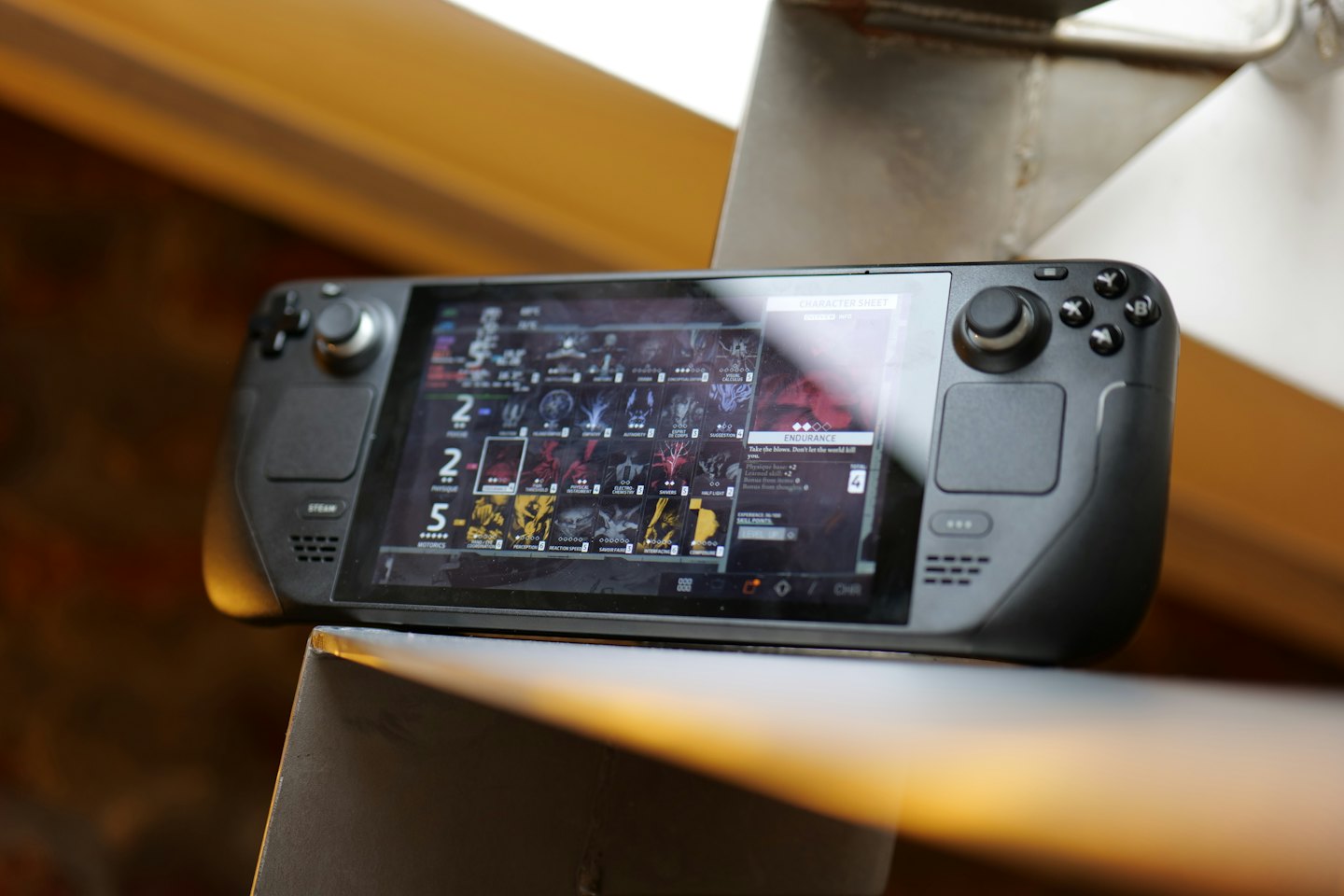 Black handheld gaming device rests on a metal beam.